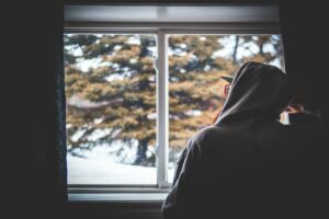 man-looking-through-window-in-the-winter