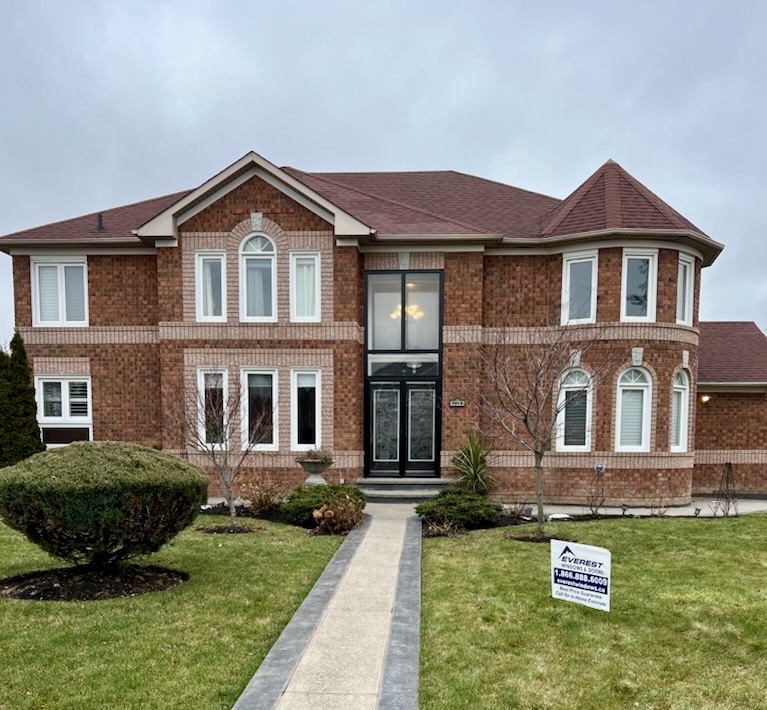 A large brick home with variously designed windows and a double entry front door